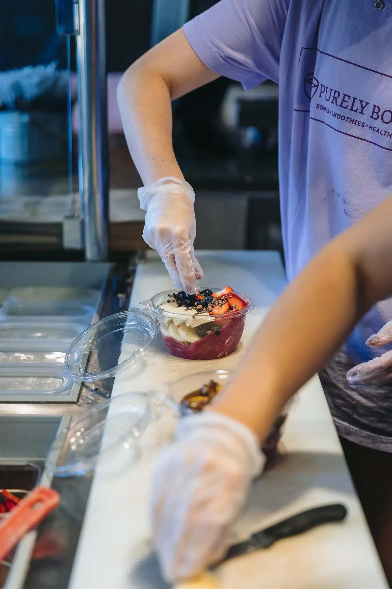 A Purely Bowls team member topping a fresh bowl